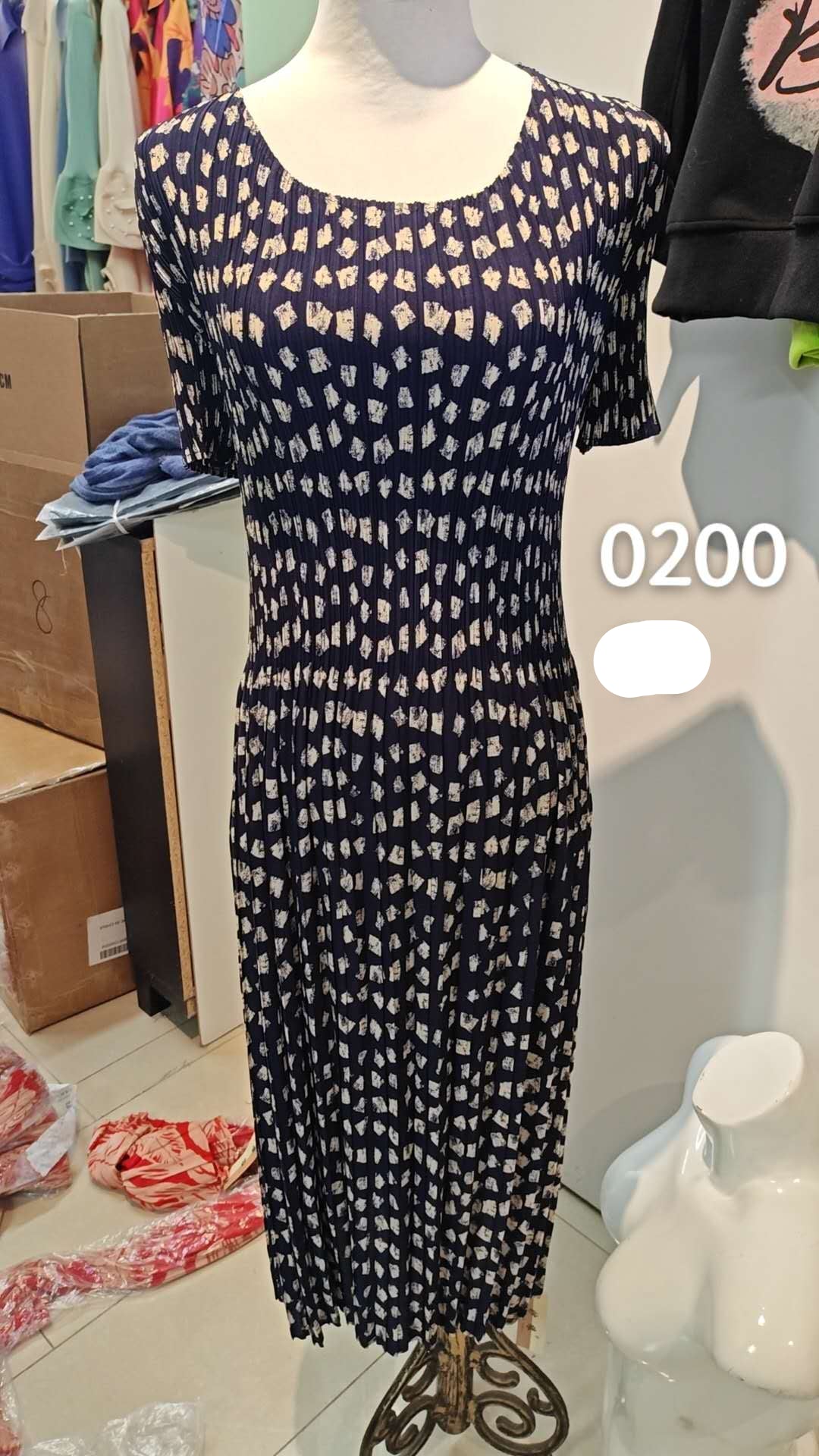 Black dress with white pattern on a mannequin in a store setting.
