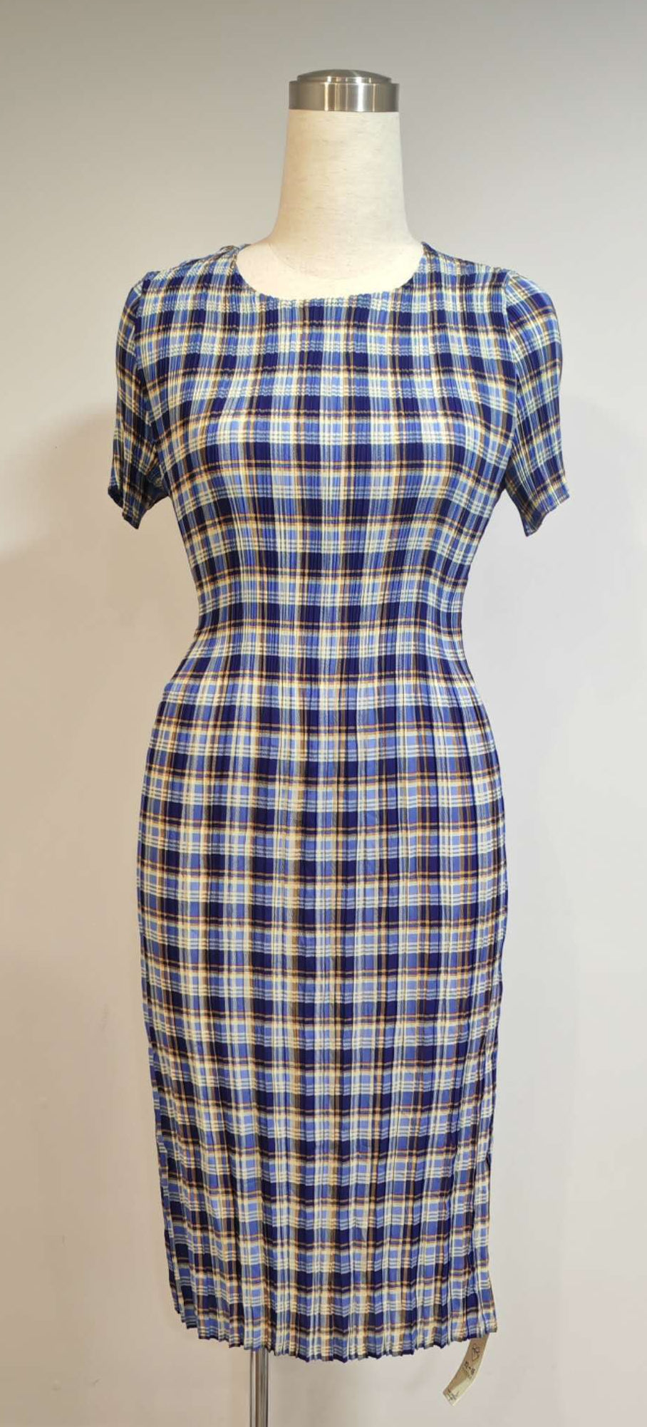 Plaid dress on a mannequin against a plain wall with visible Honor 100 Pro camera branding.