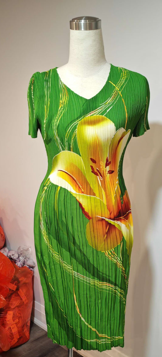 Green dress with floral design on a mannequin against a white wall.