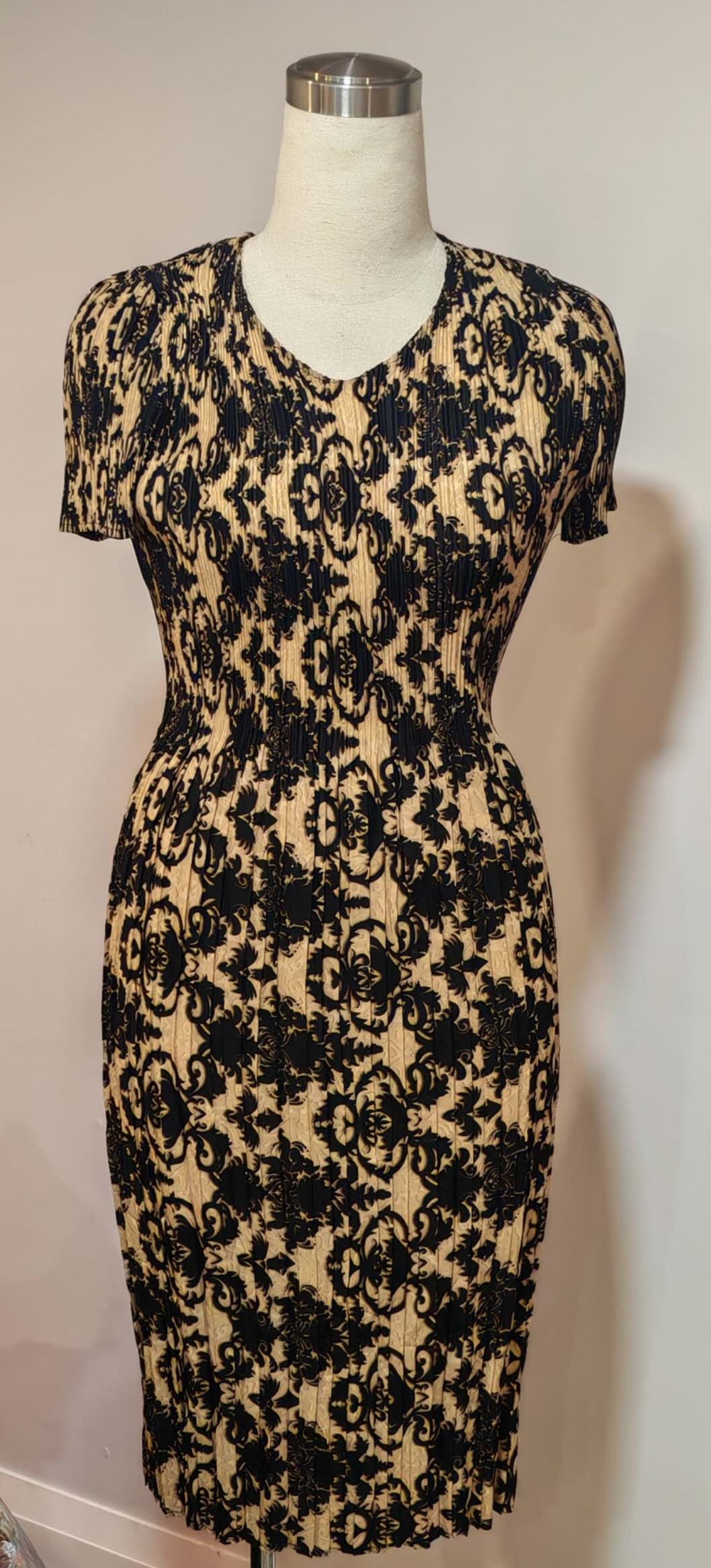 Black and beige floral patterned dress on a mannequin against a white wall.