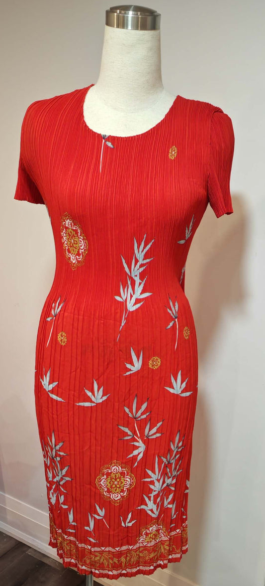 Red dress with white floral patterns on a mannequin against a plain wall.