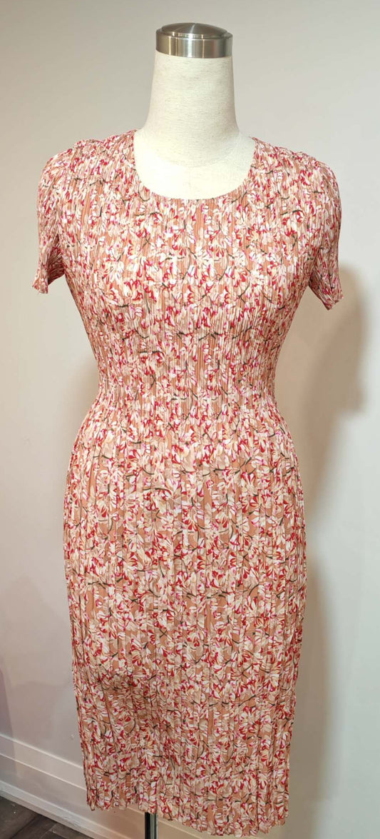 Floral dress on a mannequin against a plain wall with a visible phone reflection.
