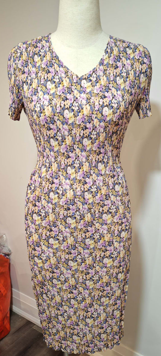 Floral dress on a mannequin against a plain wall with a visible phone reflection.